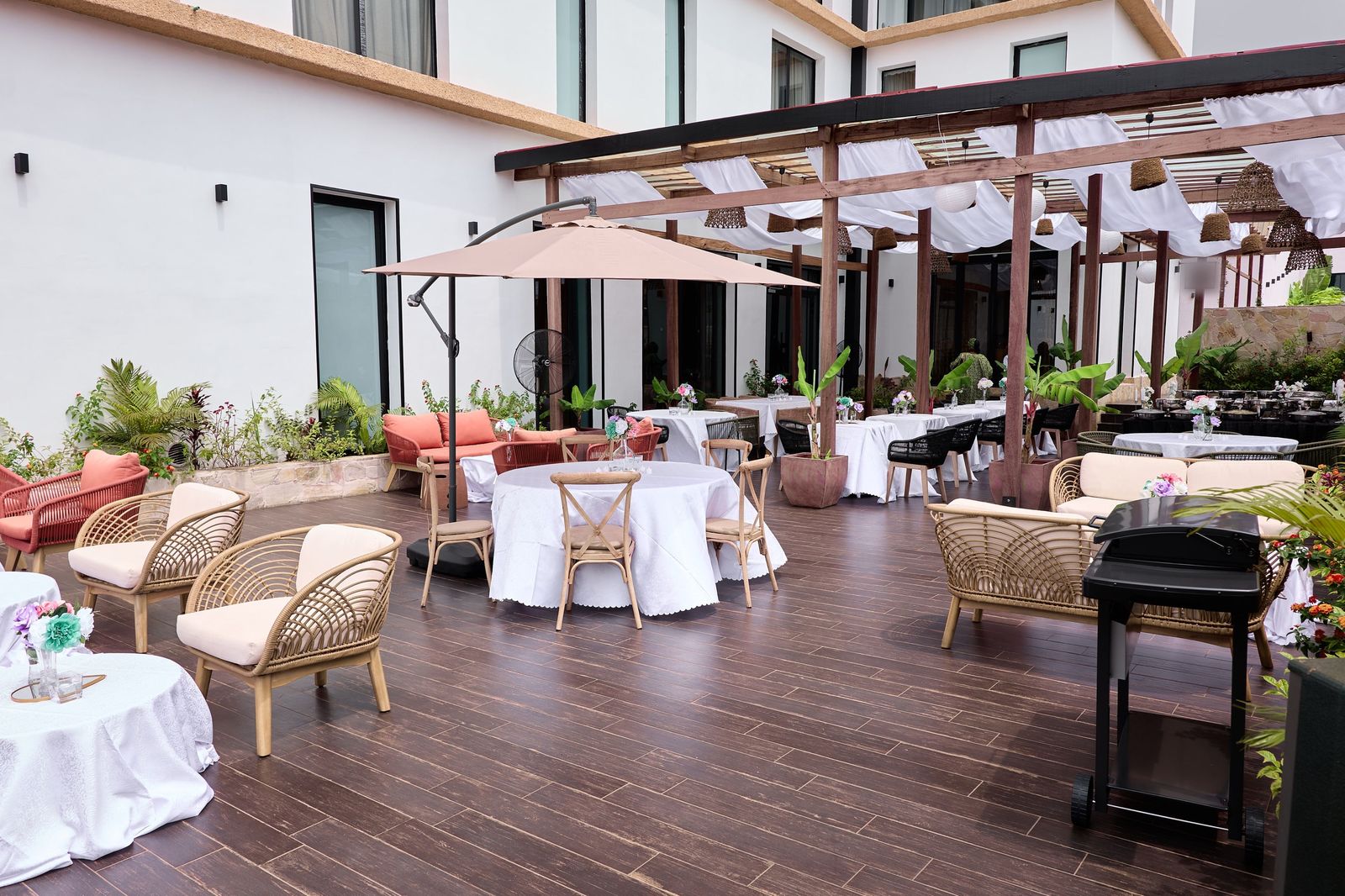 La terrasse dressée pour une réception, voilages tendus sous la pergola